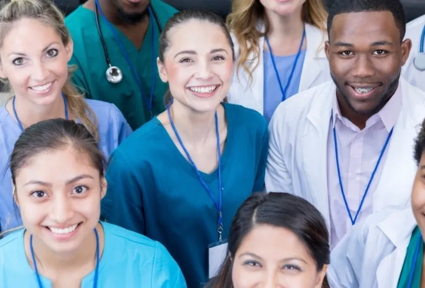 A group of doctors and nurses are smiling for the camera.