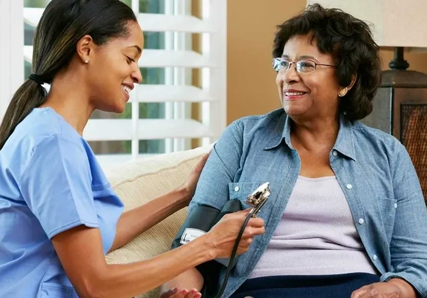 A woman is taking the blood pressure of another person.