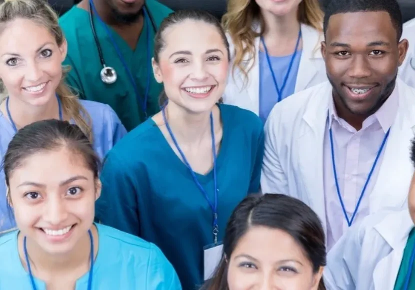 A group of doctors and nurses are smiling for the camera.